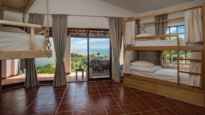 Una habitación con dos literas, un cristalera corrediza que da a un espacio exterior y vistas al mar.