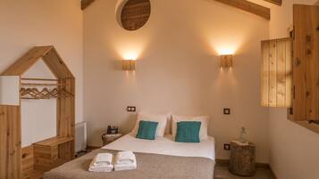 A bedroom with a bed, two wall-mounted lights, a wooden headboard, a mirror, and a wooden wardrobe.