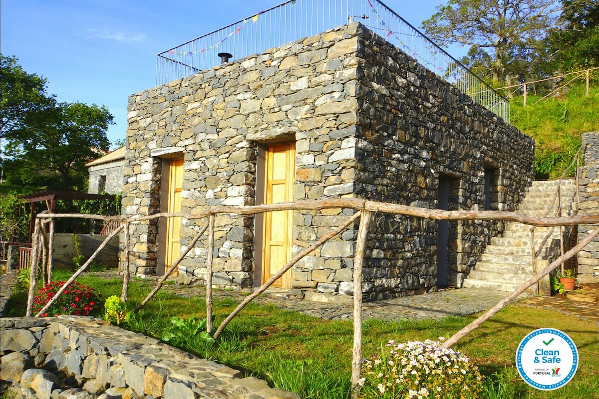 Un bâtiment en pierre avec deux portes en bois, un petit escalier et une clôture en métal.