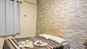 Una habitación de hotel con cama, aire acondicionado de pared y suelo de baldosas.