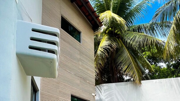 Un edificio moderno con fachada texturizada, piscina y sillas de descanso.