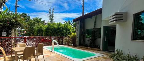 Ein Poolbereich mit Tisch und Stühlen, Liegestühlen und einer gefliesten Terrasse.