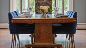 A dining room with a large wooden table, blue upholstered chairs, and a chandelier. - Seven Hills Inn (Lenox)