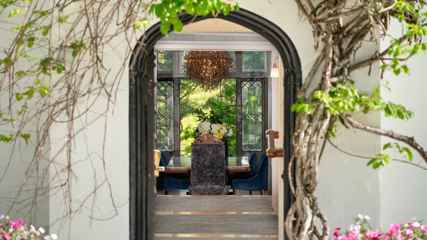 An indoor dining area with a central table and chairs, surrounded by a decorative archway and greenery. - Seven Hills Inn (Lenox)