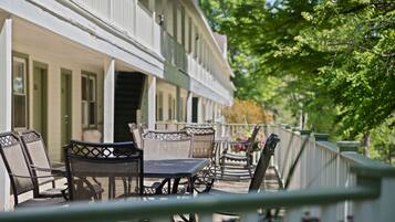 A patio with outdoor seating, a railing, and a building with multiple windows.