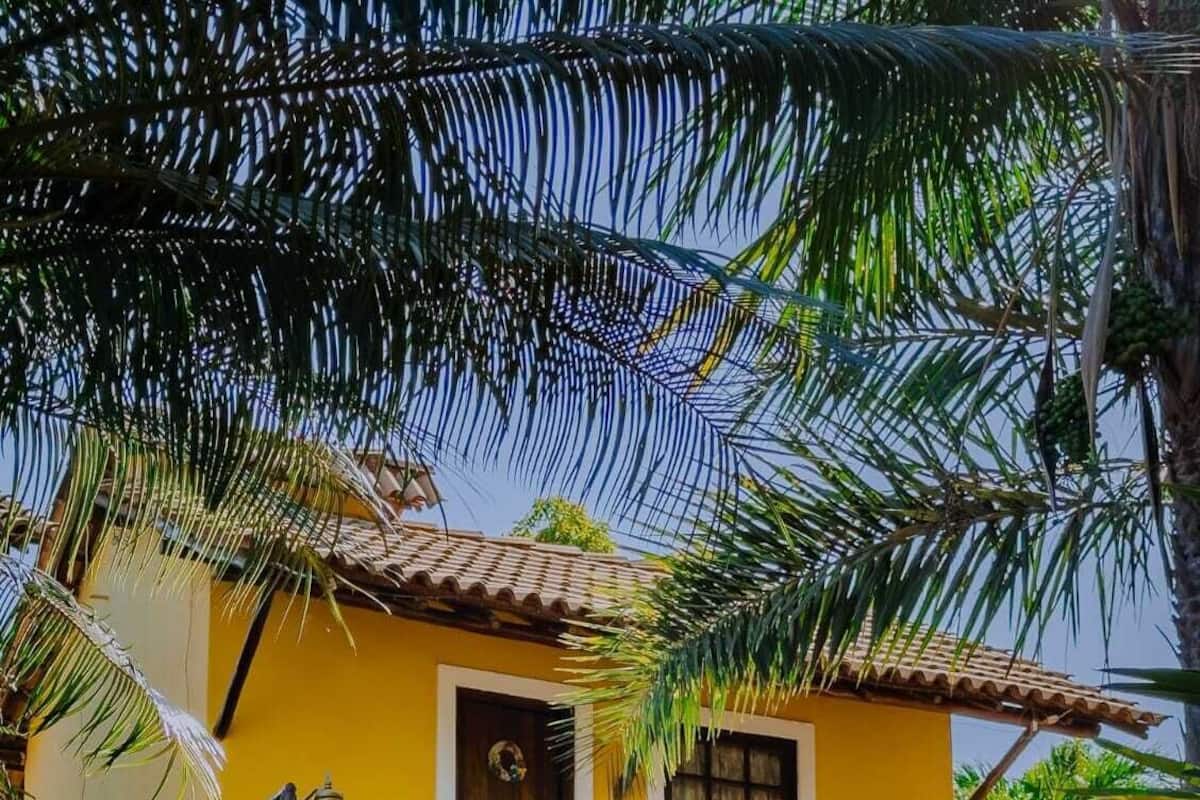 Un edificio amarillo con techo de tejas, una puerta de madera y una escalera que lleva a la entrada.