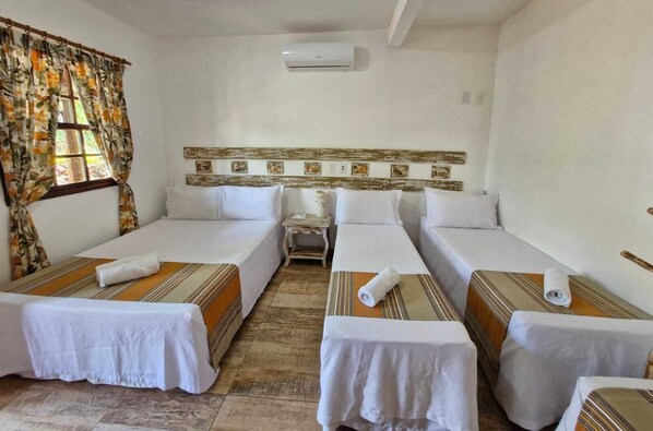 A hotel room with three single beds, a small table, and a window with curtains. - Pousada Mirante de Lençóis (Lençóis)