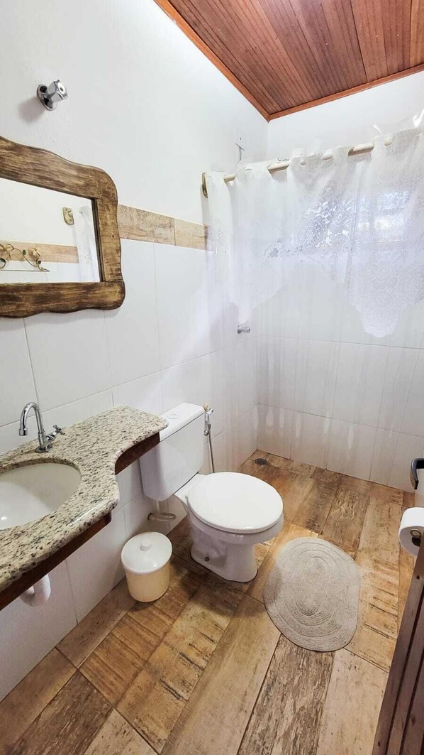 Un baño con lavamanos de granito, inodoro y cortina de ducha.