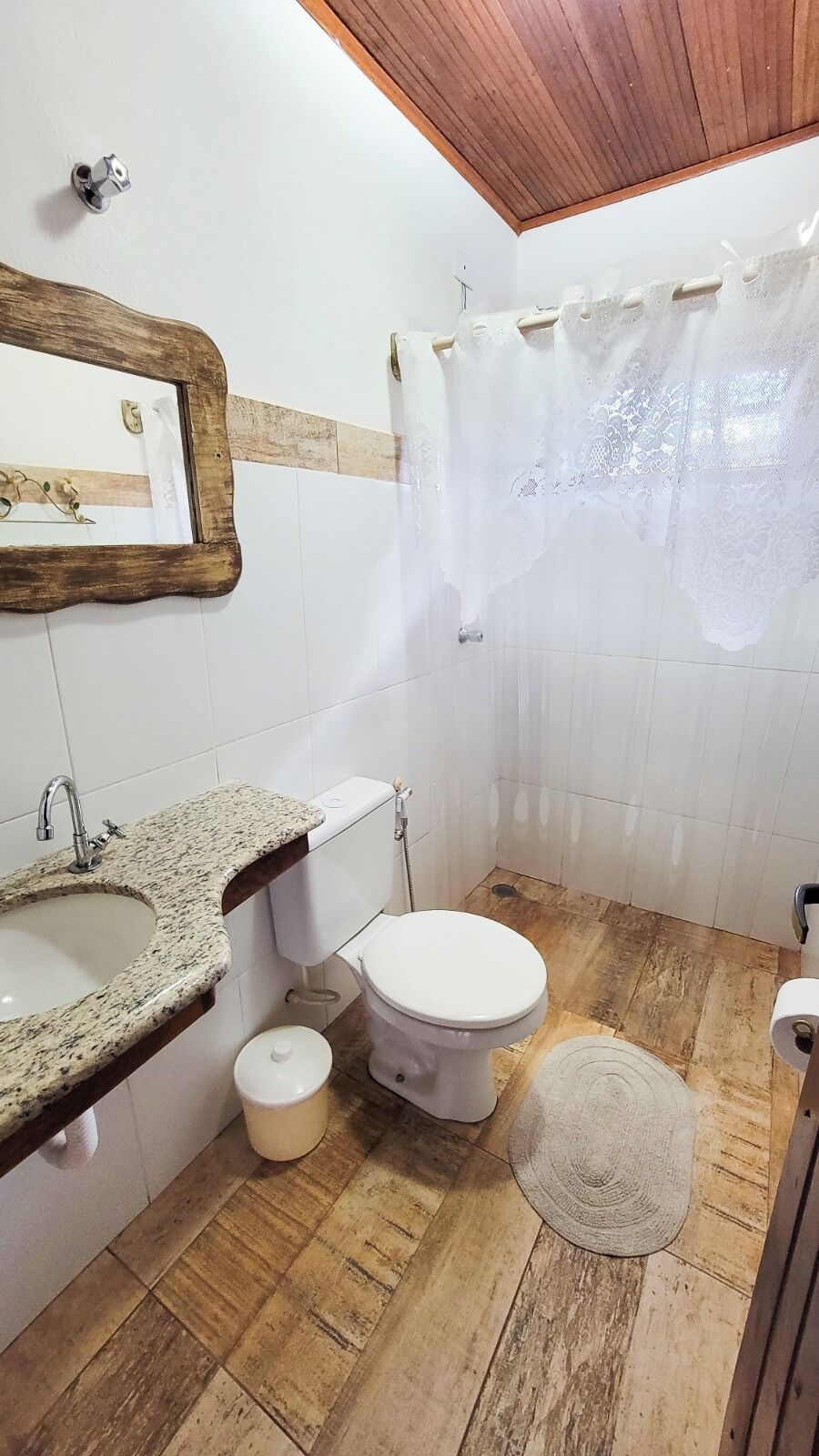 A bathroom with a granite sink, toilet, and shower curtain.