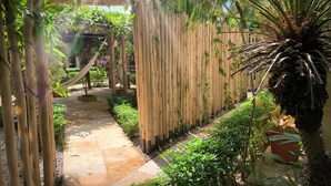 A garden pathway with a wooden pergola, bamboo fence, and various plants. - Pousada Oasis Paracuru (Paracuru)