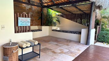 Un espacio al aire libre cubierto con techo de paja, suelo de piedra y un letrero en portugués.