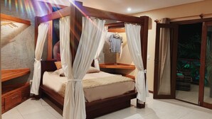 A bedroom with a four-poster bed, a wooden bench, a small table, and a sliding glass door leading to a balcony. - Pousada Oasis Paracuru (Paracuru)