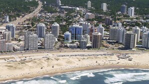 Un paisaje urbano costero con edificios altos, una playa y una carretera que conduce hacia la ciudad.