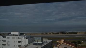 A hotel with a sign reading "HOTEL Granovam" on the rooftop, overlooking a beach and a road.