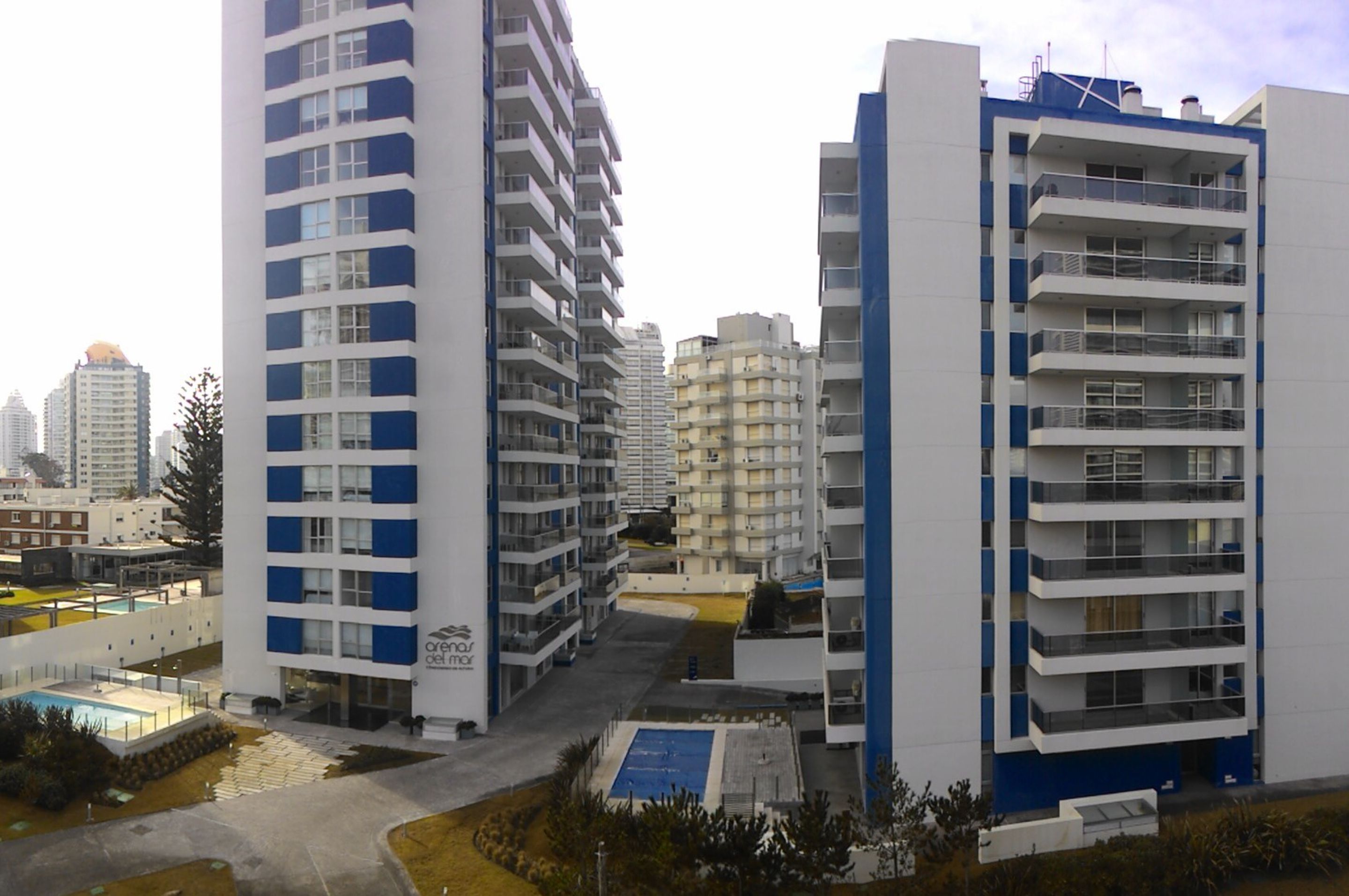 A modern apartment building with multiple balconies and a rooftop pool area.
