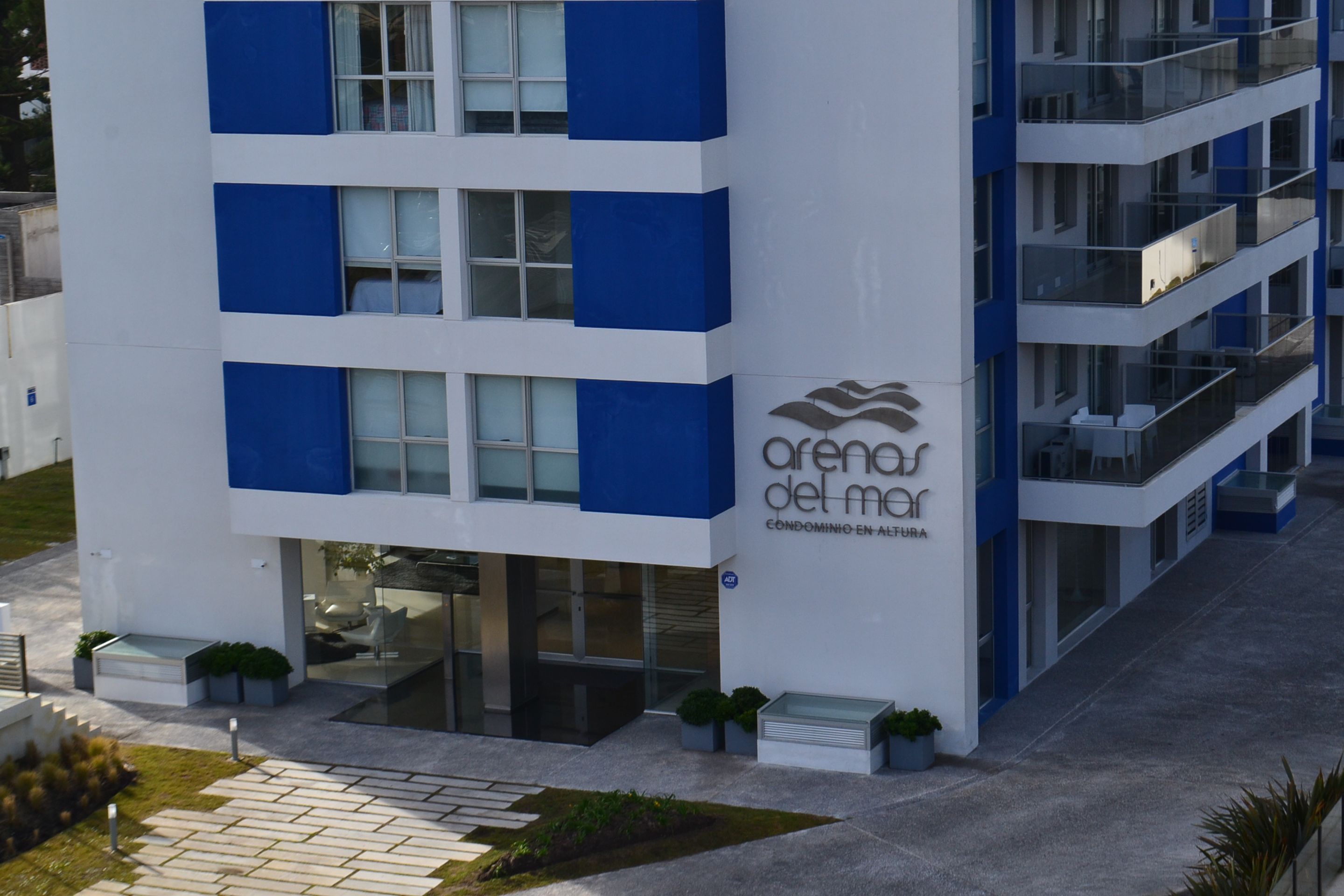 A modern building with a blue and white facade, featuring balconies and large windows.