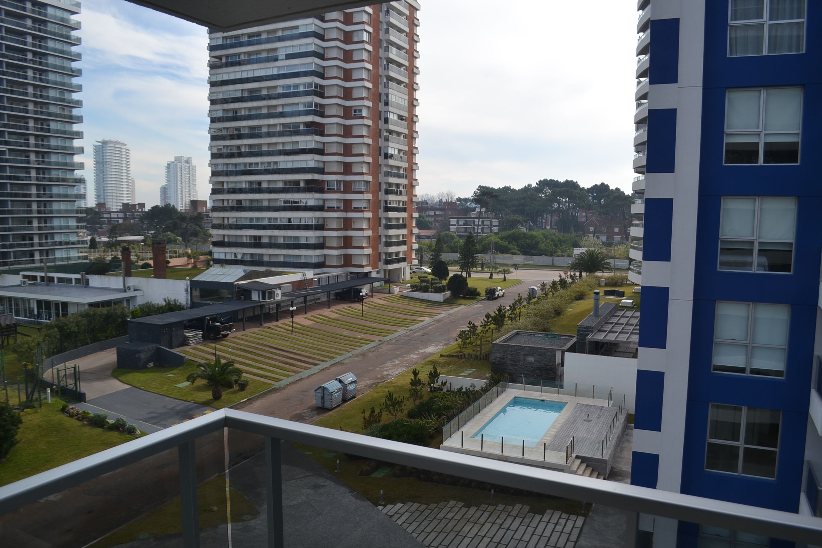 A residential building with a pool, a well-maintained lawn, and a parking area.