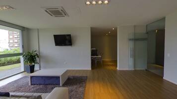 Una sala de estar moderna con un televisor de pantalla plana, una planta en maceta y un ventanal con vistas al exterior.