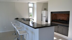 Una cocina moderna con una isla central, taburetes de bar, un refrigerador y un horno empotrado.