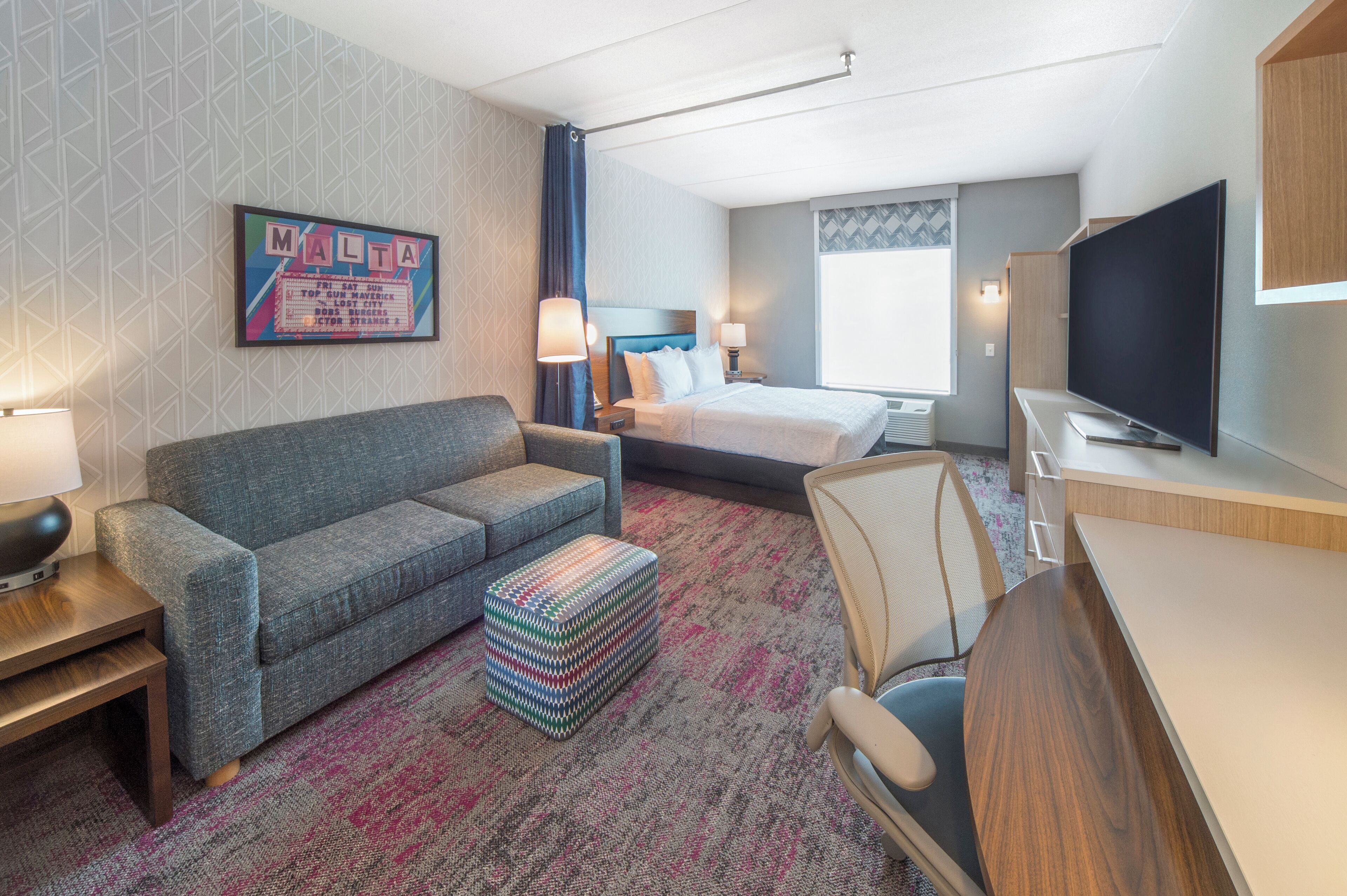 A hotel room with a bed, a sofa, a TV, and a desk.