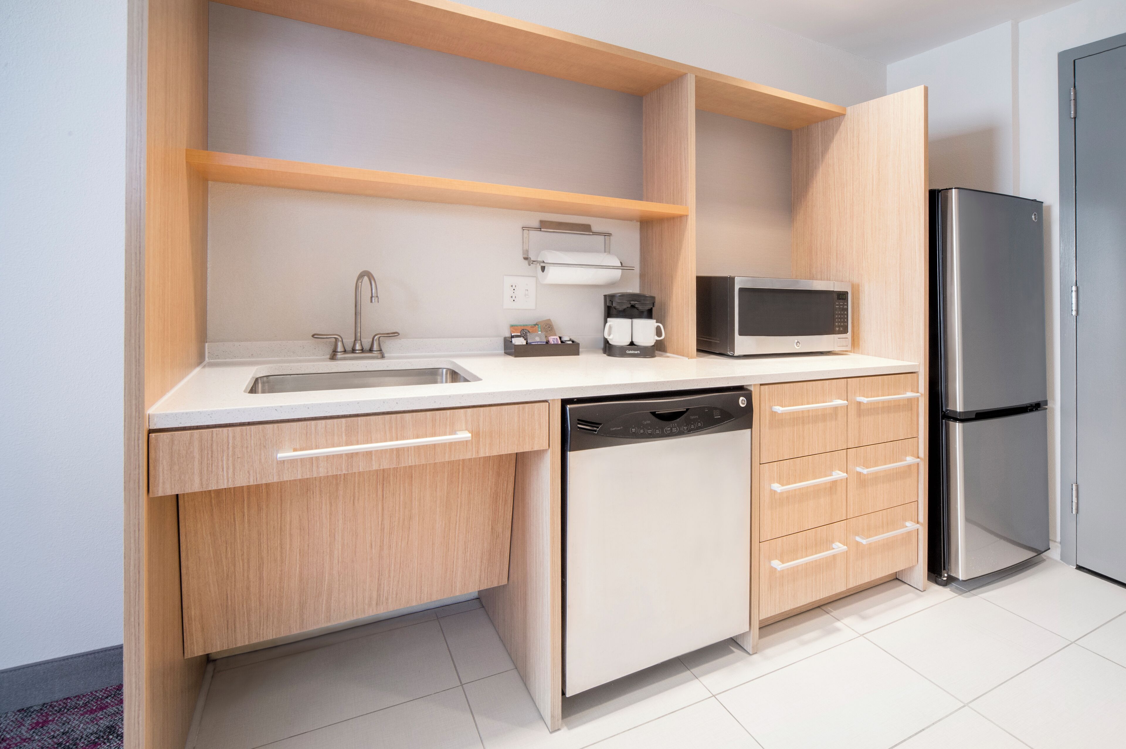 A modern kitchen with a dishwasher, microwave, and refrigerator.