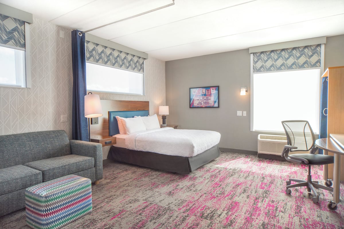 A hotel room with a bed, a sofa, a desk, and a chair.