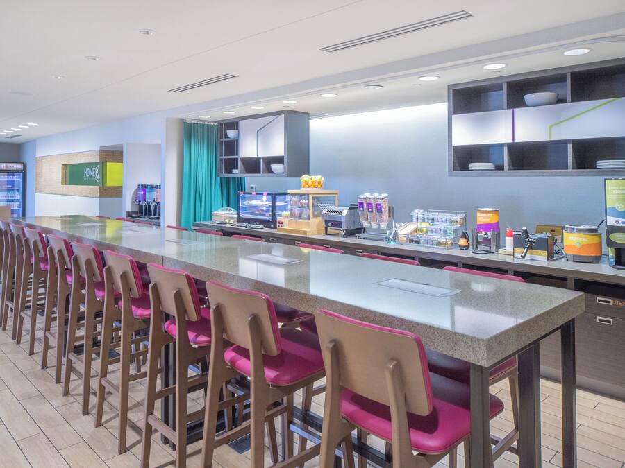 Un área de cocina moderna con una encimera larga, taburetes de bar y diversos electrodomésticos.