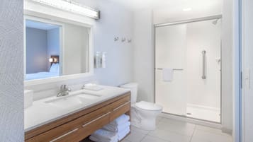 Une salle de bain moderne avec un grand miroir, deux lavabos, des toilettes et une douche à parois de verre.