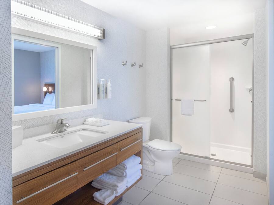 Une salle de bain moderne avec un grand miroir, deux lavabos, des toilettes et une douche à parois de verre.
