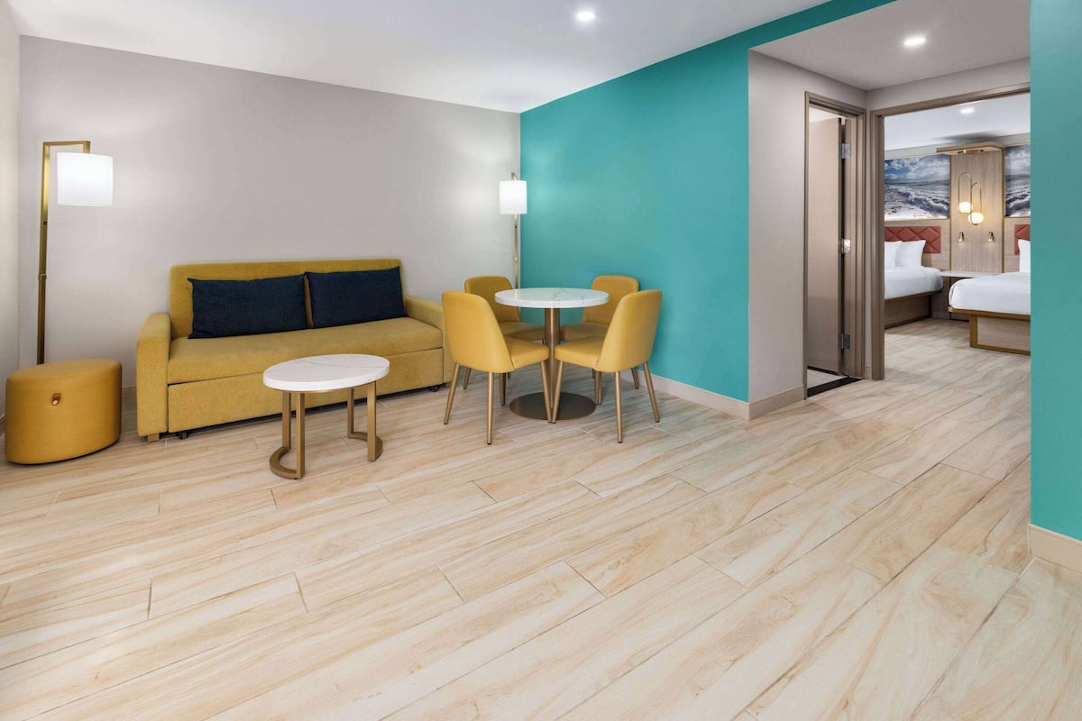 Habitación de hotel moderna con sofá, una mesa redonda con sillas, cama y vista al mar.