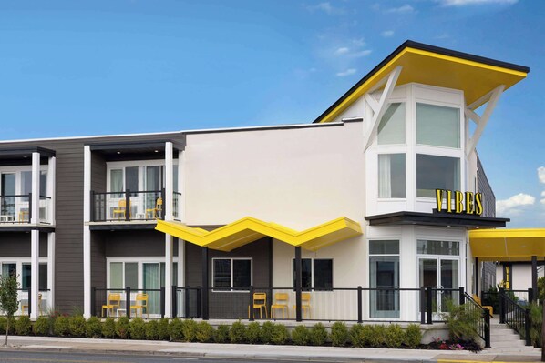 Un edificio moderno con un toldo amarillo y la palabra "VIBES" en la fachada.