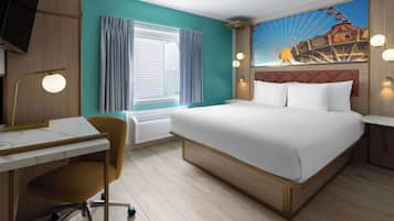 Ein Hotelzimmer mit Bett, Schreibtisch, Stuhl und einem großen Fenster mit Vorhängen.