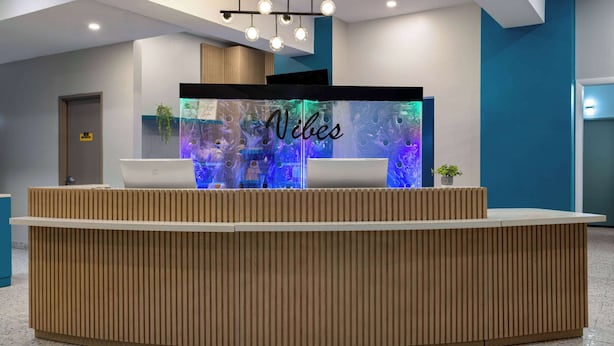 Una recepción con un letrero que dice 'Vibes', una computadora portátil y una planta pequeña.