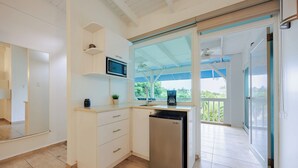 A modern kitchen with a built-in microwave, a coffee maker, and a dishwasher. It features a large window and a sliding glass door leading to an outdoor area.