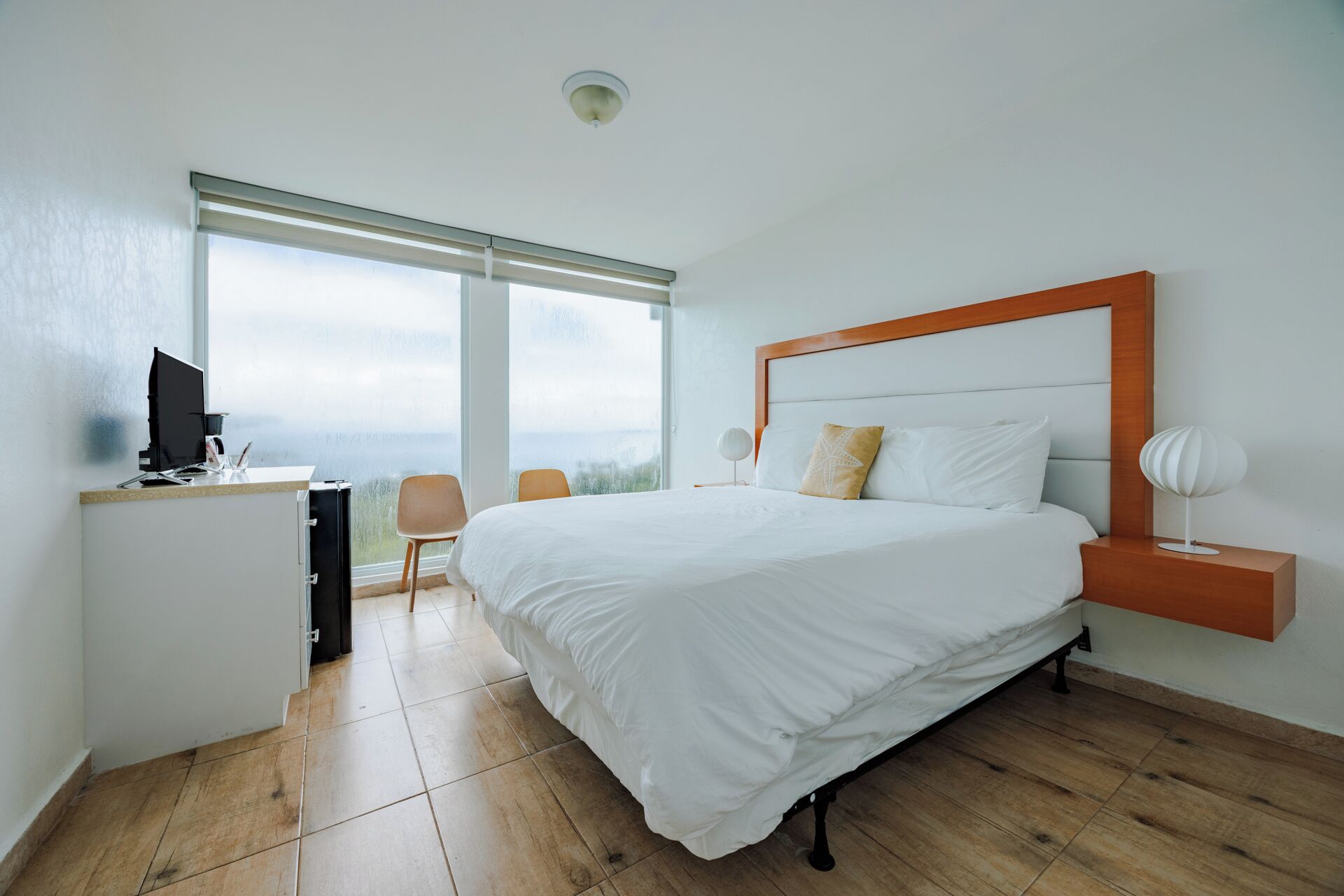 Une chambre avec un grand lit, un bureau avec un ordinateur et une chaise.