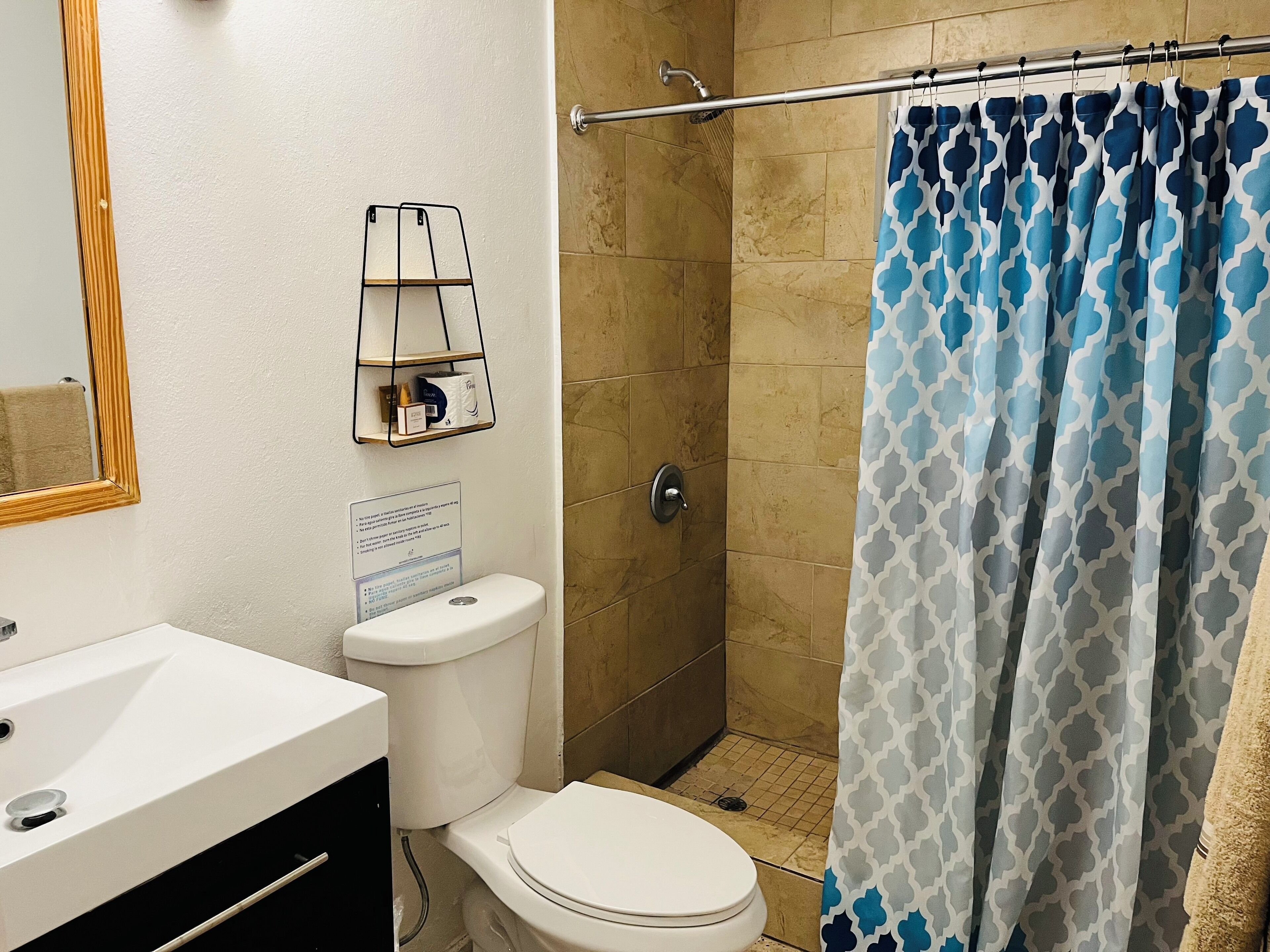A bathroom with a white sink, toilet, and shower. There is a towel rack with a mirror above the sink.