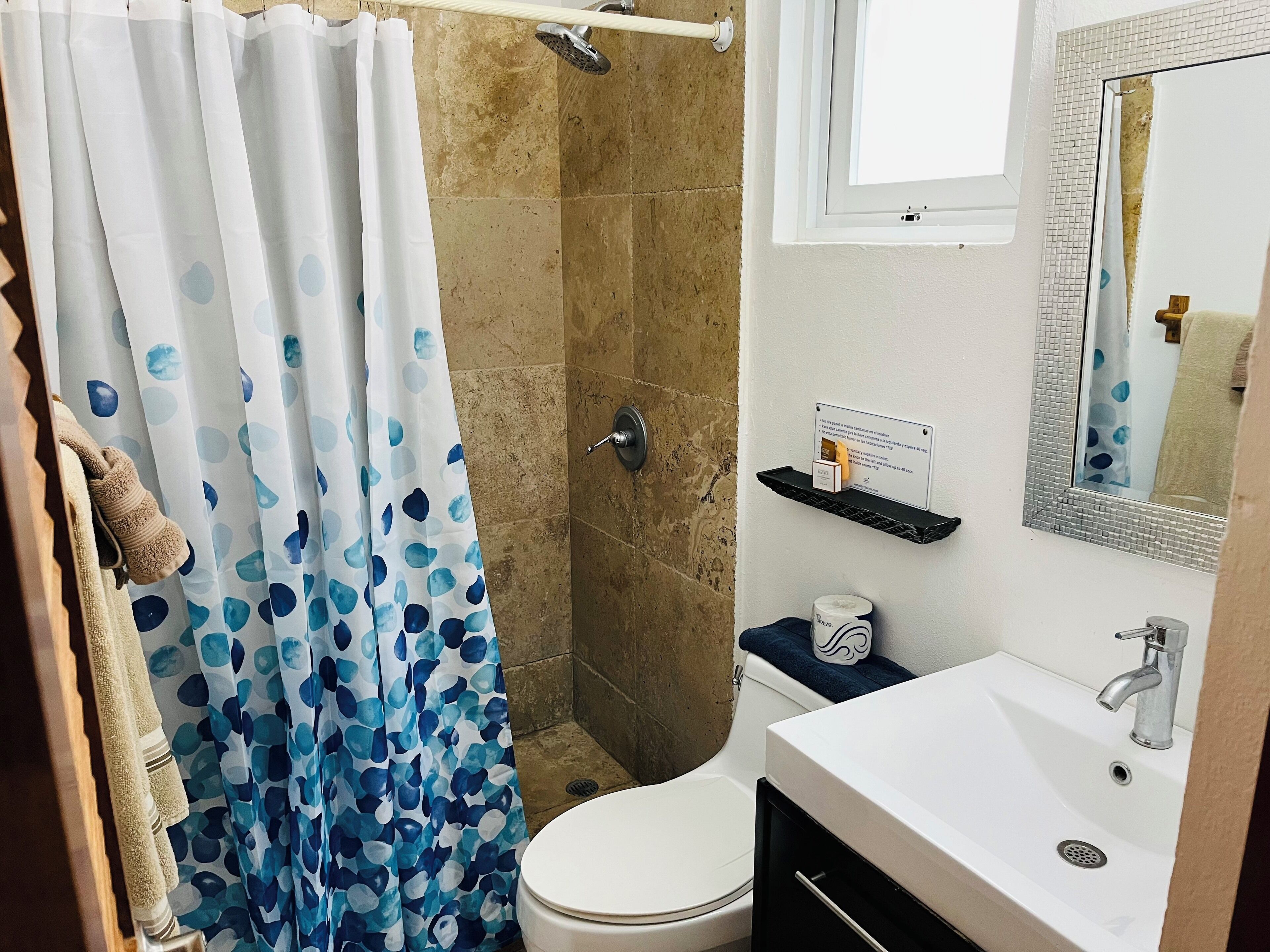 A bathroom with a shower curtain, a toilet, a sink, and a mirror.