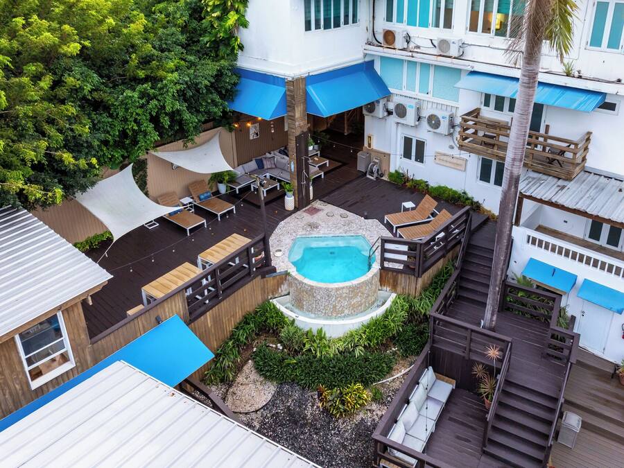 A rooftop pool area with lounge chairs, a hot tub, and a wooden deck.