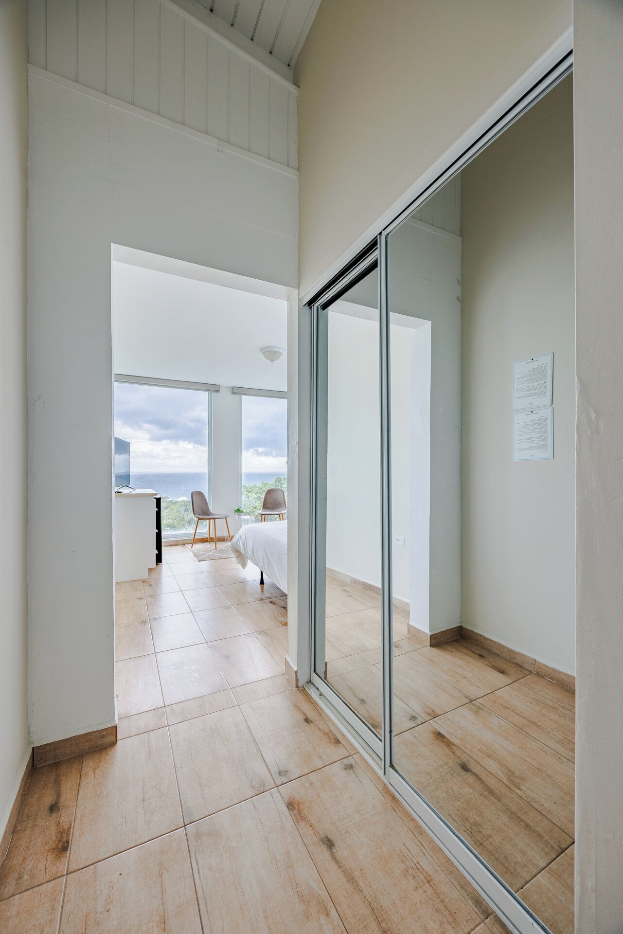 A spacious room with a large sliding glass door leading to a balcony with a view of the sea.