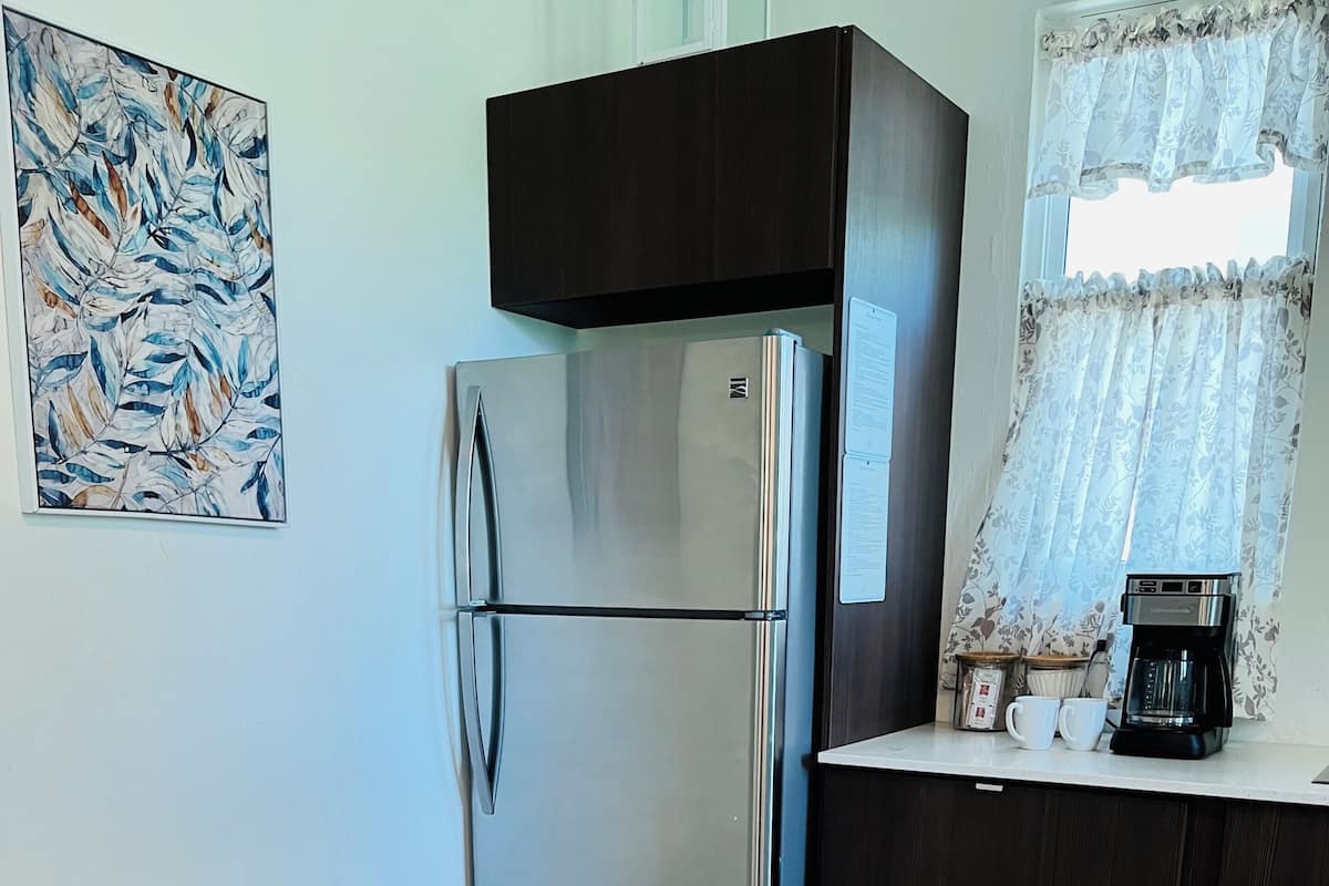 A modern kitchen with a stainless steel refrigerator, a coffee maker, and a dining table with chairs.