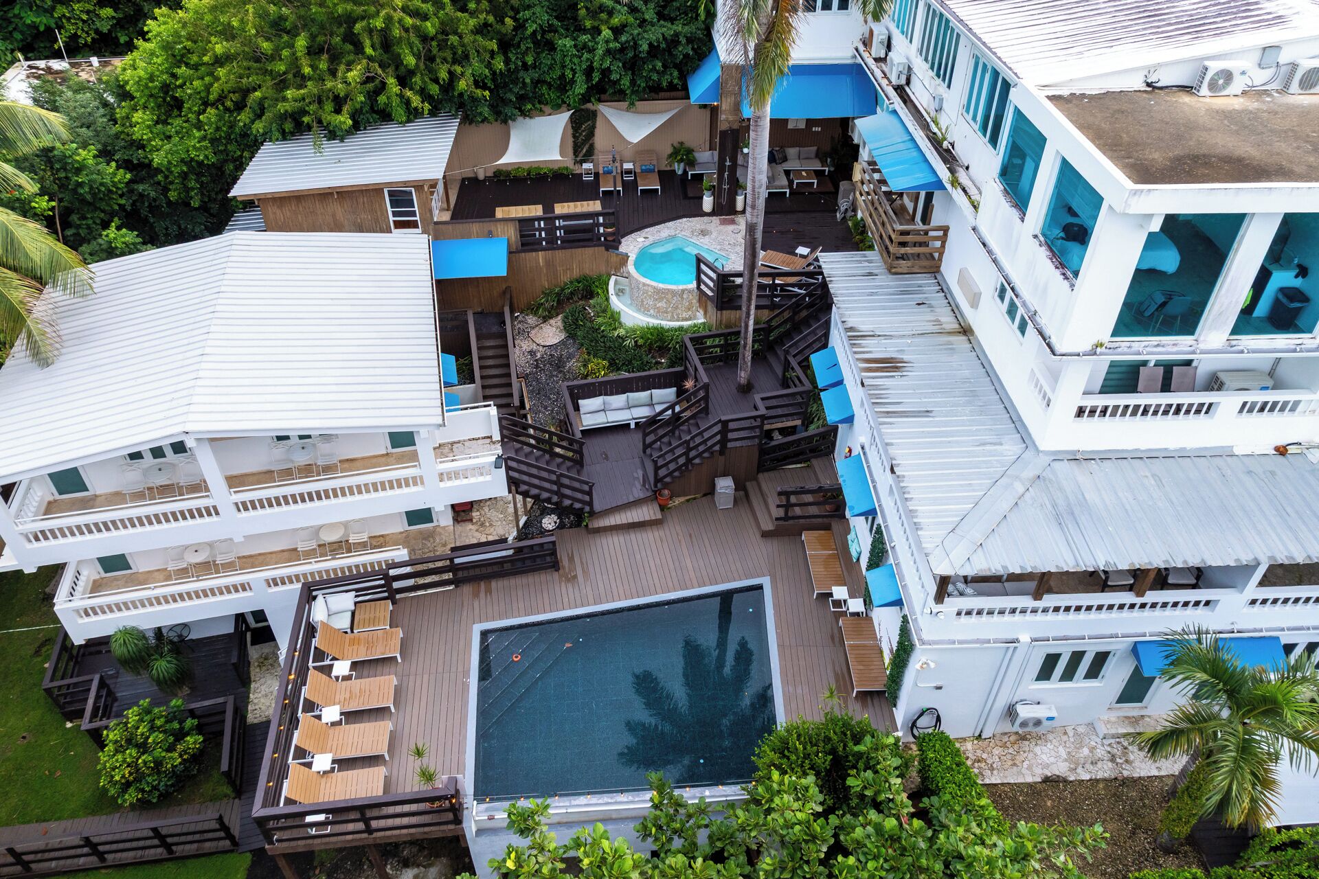 A multi-story hotel with a rooftop pool, outdoor seating areas, and a well-maintained garden.