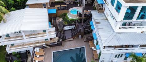A multi-story hotel with a rooftop pool, outdoor seating areas, and a well-maintained garden.