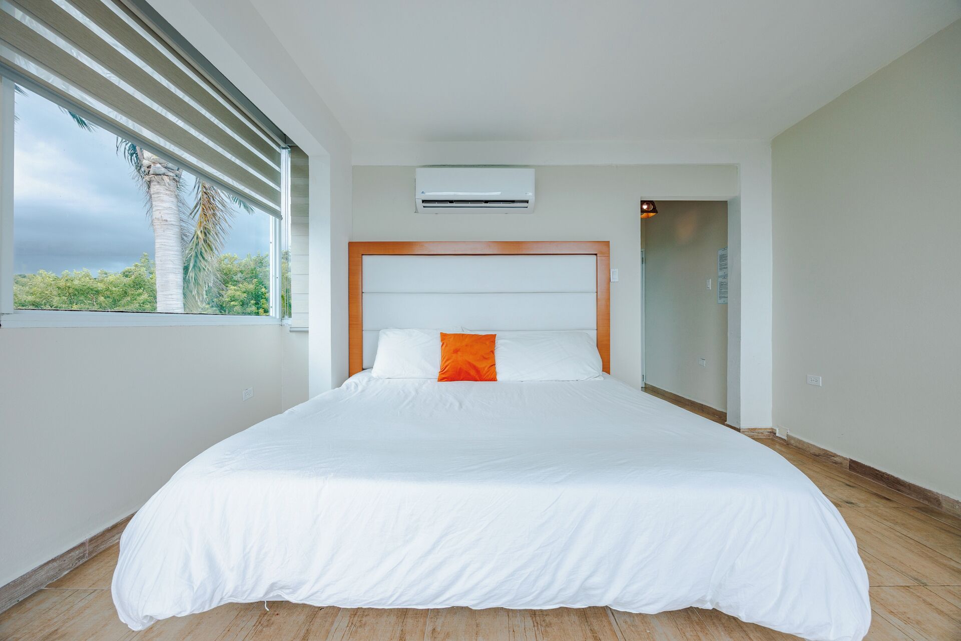 Una habitación de hotel moderna con una cama grande, un equipo de aire acondicionado y vistas al exterior.