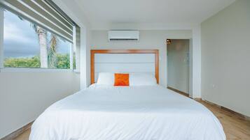 Una habitación de hotel moderna con una cama grande, un equipo de aire acondicionado y vistas al exterior.