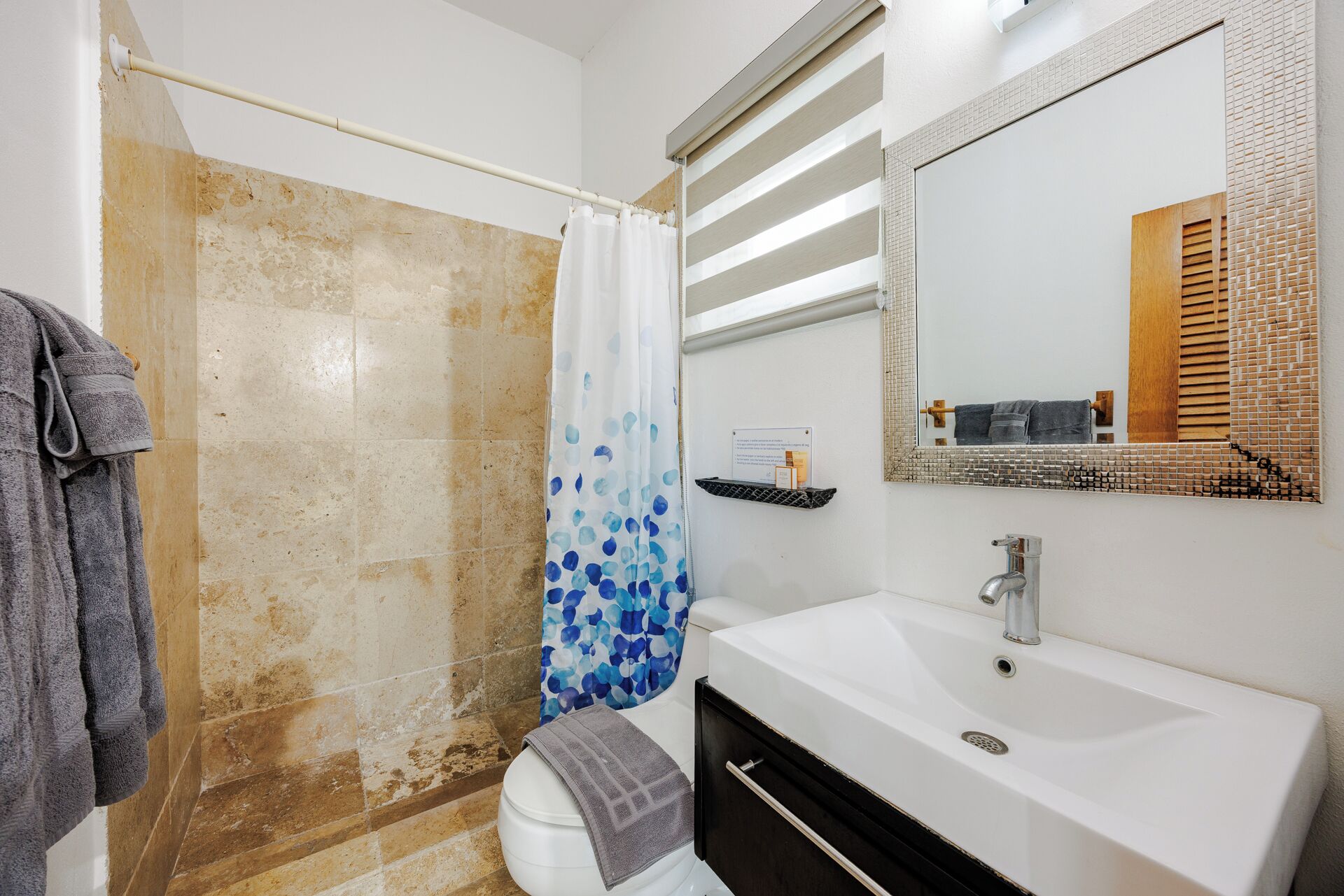 A bathroom with a shower, a sink, and a mirror.