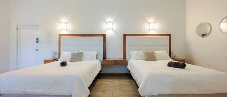 Habitación de hotel con dos camas, cabeceros de madera e iluminación de pared.