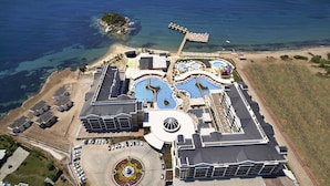 Vue aérienne d’un complexe hôtelier doté de plusieurs piscines, d’un parking et d’une plage.
