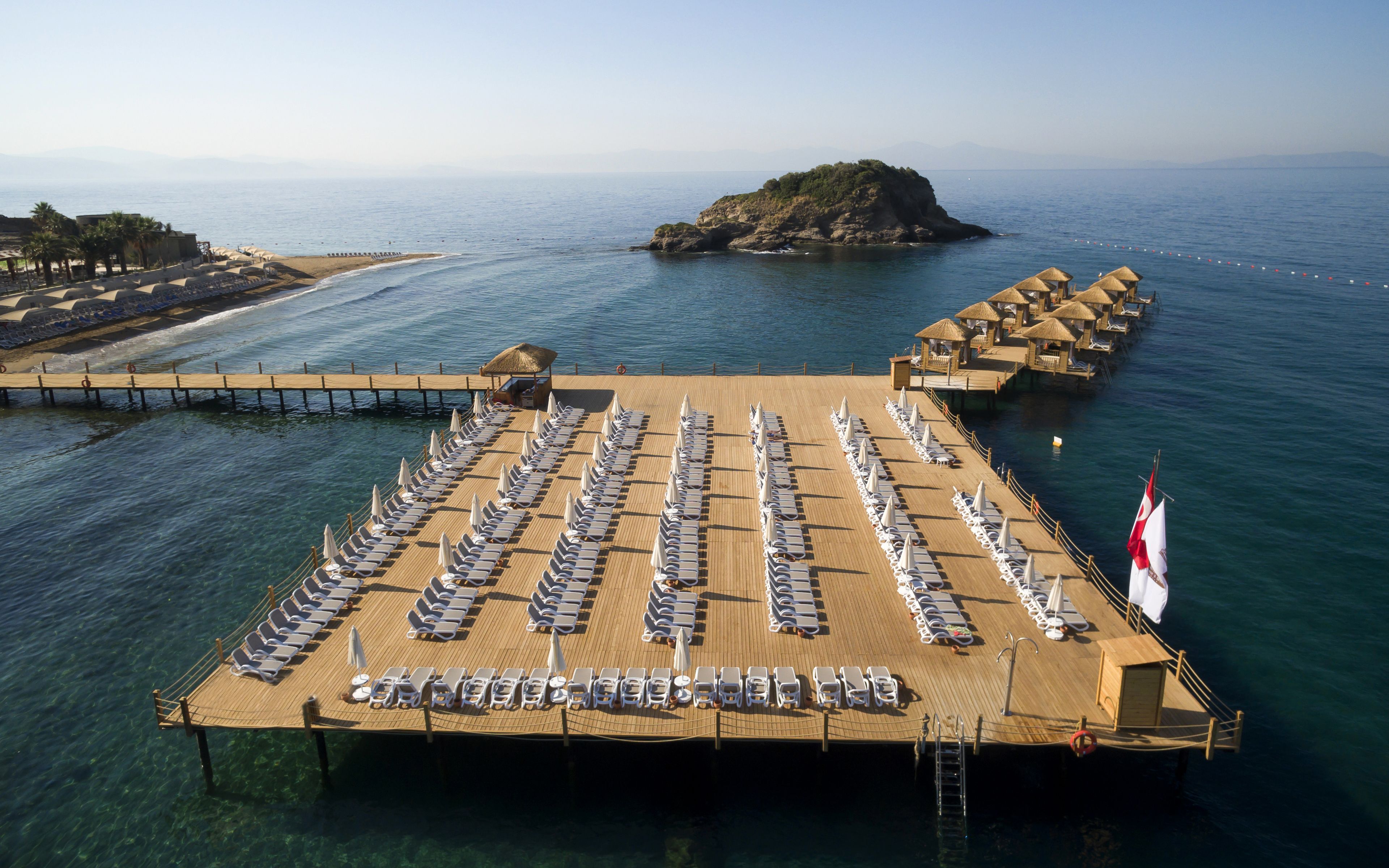 A deck with rows of sun loungers and umbrellas, a lifebuoy, and a flag.