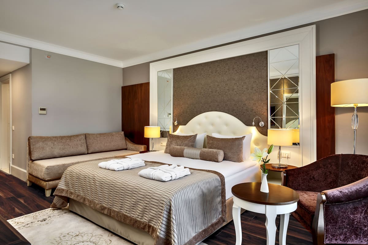 Une chambre d’hôtel avec un grand lit, un canapé, une petite table et une chaise.