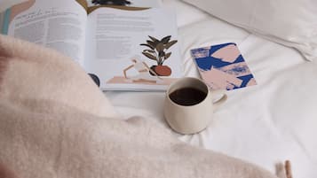A book, a cup of coffee, and a card on a bed.